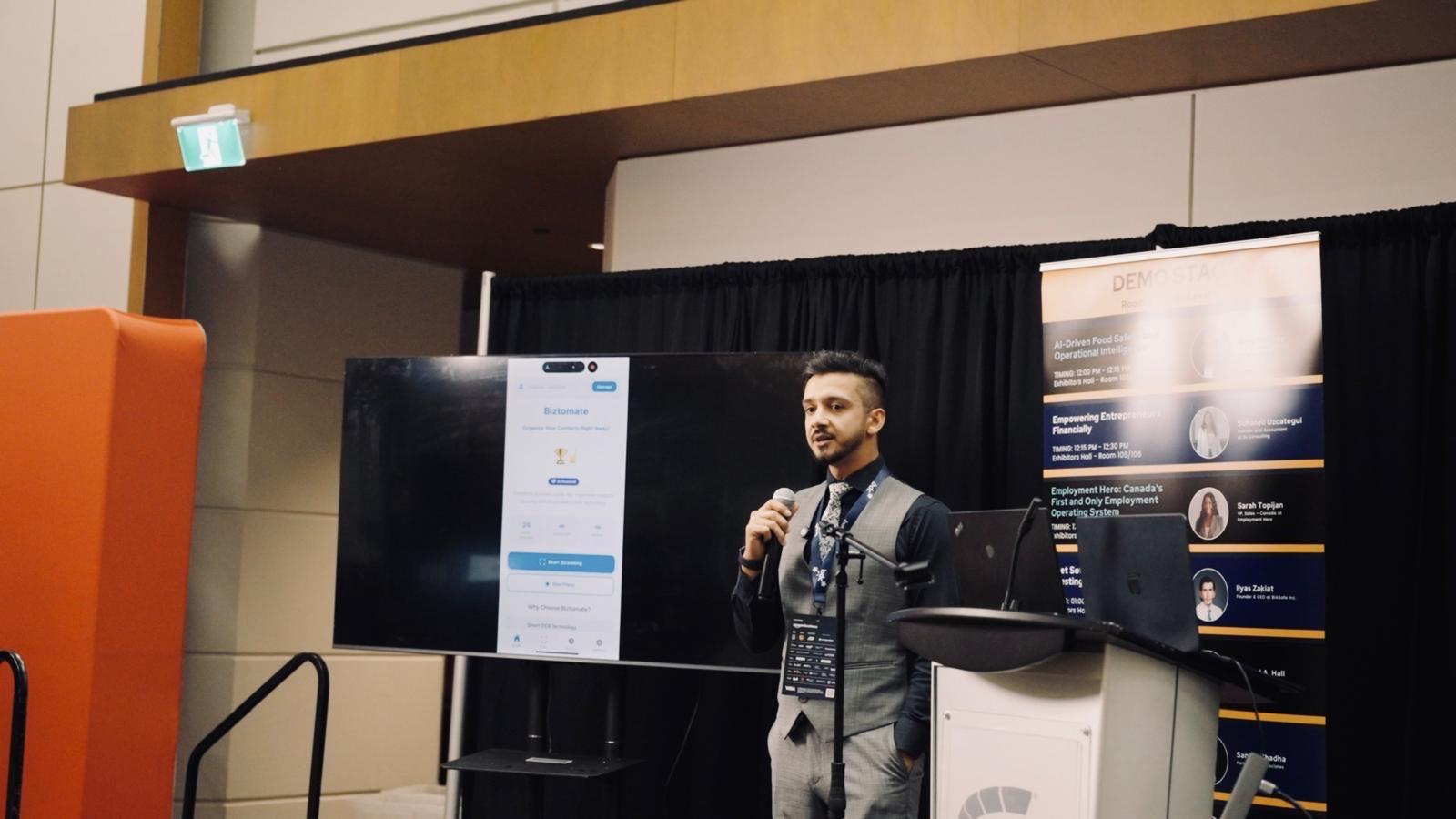 Latif Rahimi on the demo stage presenting the Biztomate AI business card scanner.